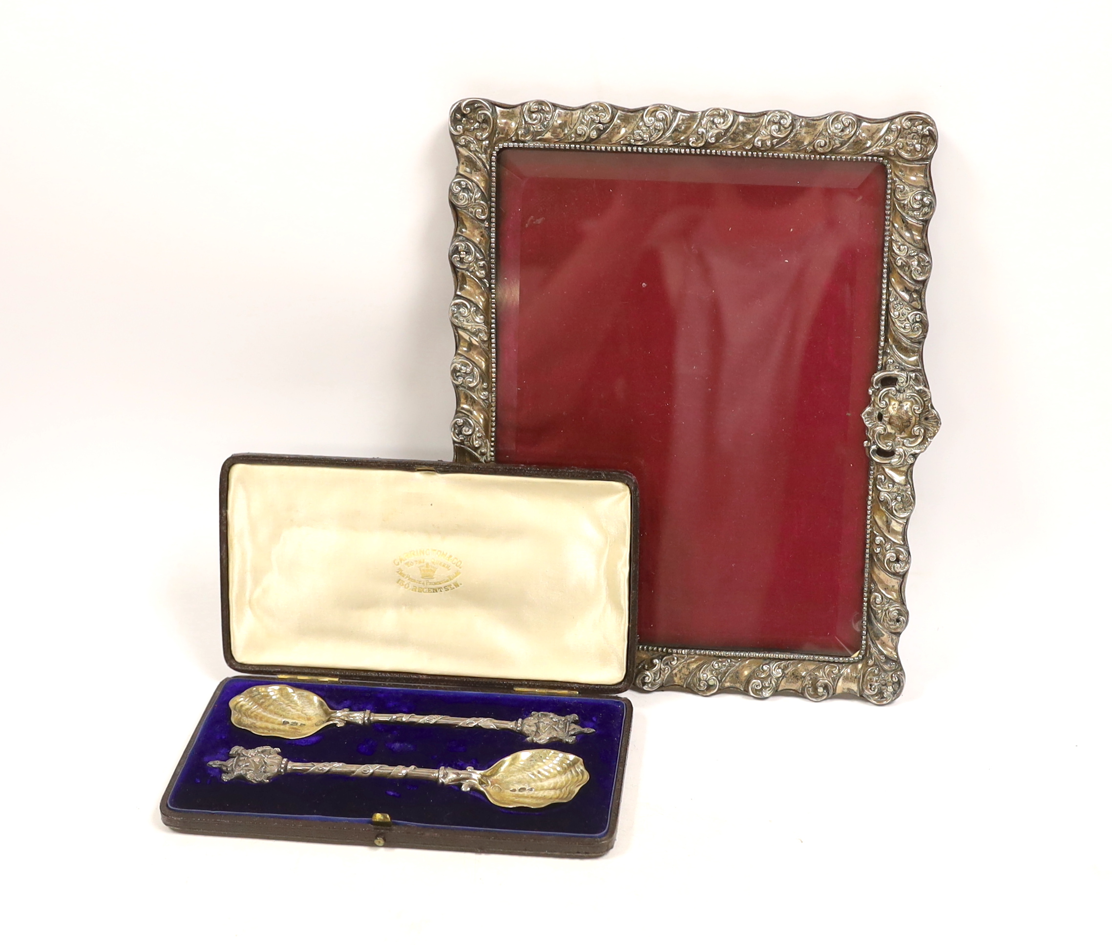 A Victorian cased pair of silver spoons with armorial terminals, Carrington & Co, London, 1903, 18.6cm, together with a late Victorian silver mounted photograph frame, Henry Matthews, Birmingham, 1899, width 24.3cm.